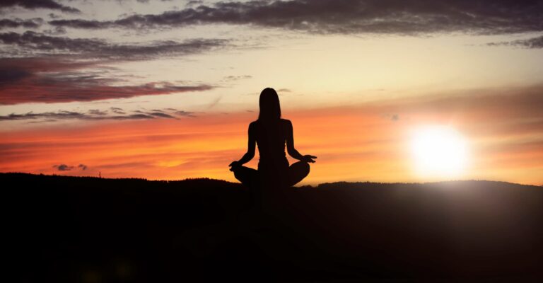 silhouette of woman meditating at sunset